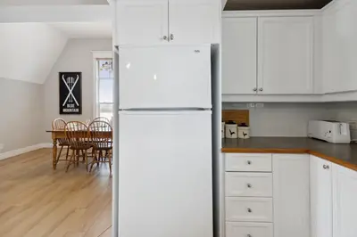 a white refrigerator in a kitchen with a table at 3BR Snowbridge Chalet in Blue with Golf Course View in Collingwood