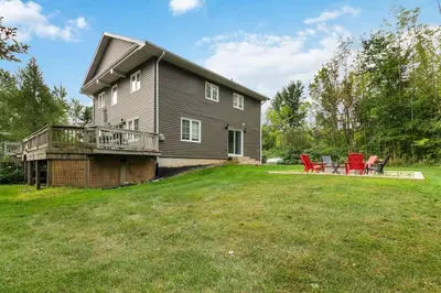 a house with a deck and red chairs on a yard at Scandia Retreat with Hot Tub, Sauna and Fire Pit in Blue Mountains