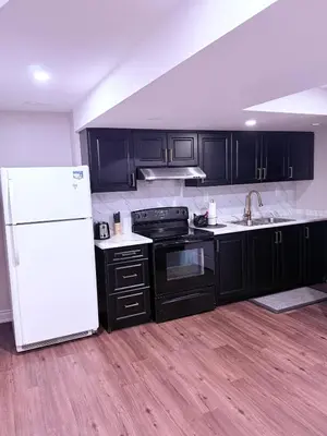 a kitchen with black cabinets and a white refrigerator at Spacious basement in Mississauga