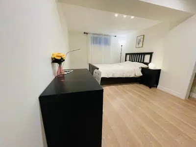 a bedroom with a bed and a black dresser with flowers on it at MT house in Mississauga