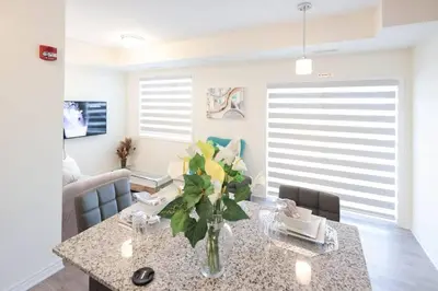 a dining room with a table with a vase of flowers at Luxurious Condo Apartment 1BR-1BA-1Office free parking in Brampton