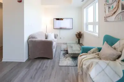 a living room with two chairs and a flat screen tv at Luxurious Condo Apartment 1BR-1BA-1Office free parking in Brampton