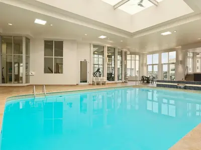 a large pool with blue water in a room with windows at Travelodge by Wyndham Niagara Falls Fallsview in Niagara Falls