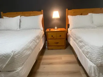 two beds in a bedroom with a lamp on a night stand at Ranch House Inn in Exeter