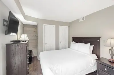 a bedroom with a white bed and a flat screen tv at Wintergreen 119 in Blue Mountains