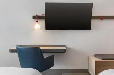 a room with a blue chair and a tv on a wall at avid Hotel - Toronto - Vaughan Southwest by IHG in Vaughan