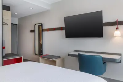 a room with a table and a tv on a wall at avid Hotel - Toronto - Vaughan Southwest by IHG in Vaughan