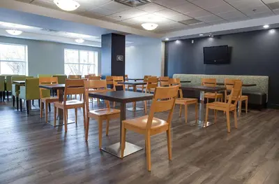 a dining room with tables and chairs and a tv at Country Inn & Suites by Radisson, Niagara Falls, ON in Niagara Falls