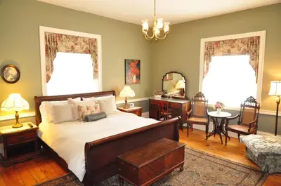 a bedroom with a bed and a table and a chair at Brockamour Manor Bed and Breakfast in Niagara on the Lake