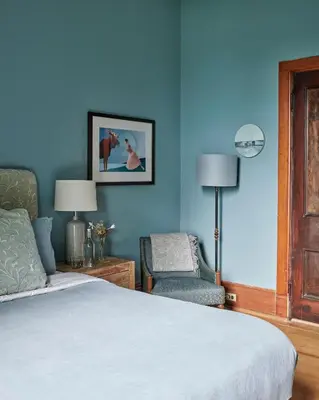 a bedroom with blue walls and a bed and a chair at The Eddie Hotel and Farm in Bloomfield