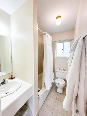 a white bathroom with a toilet and a sink at Oasis by the Bay Vacation Suites in Wasaga Beach
