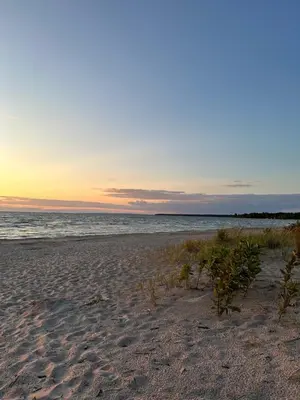 a beach with the sun setting over the ocean at Oasis by the Bay Vacation Suites in Wasaga Beach