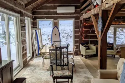 a living room with a table and a surfboard on the wall at A charming, rustic 150 year old Carriage House in Orangeville