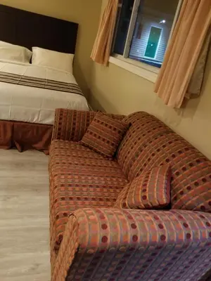 a couch in a room next to a bed at Silver Maple Motel in Haliburton