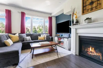 a living room with a couch and a fireplace at Modern home with a pool sauna pooltable & mountain view in Collingwood