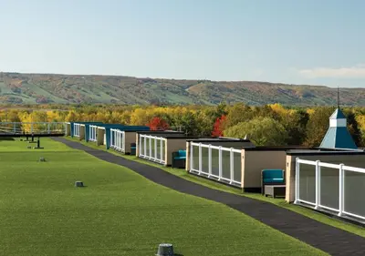 a row of buildings on a grass field with mountains in the background at Living Water Resort & Spa in Collingwood