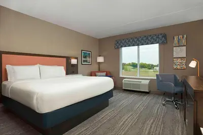 a hotel room with a bed and a desk and a window at Hampton Inn by Hilton Port Hope Cobourg in Port Hope