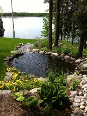 a pond in the middle of a yard with flowers at Windswept on the Trent in Campbellford