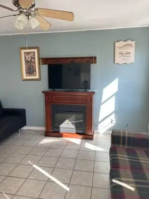 a living room with a fireplace and a ceiling fan at Wasaga Beach Cottage 2 in Wasaga Beach