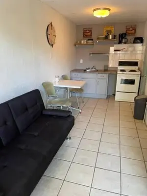 a living room with a black couch and a kitchen at Wasaga Beach Loft 4 in Wasaga Beach