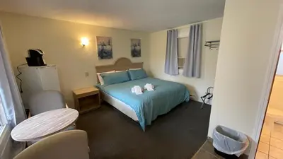 a bedroom with a blue bed and a table at Beach Club by Beach1 Motel in Wasaga Beach
