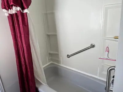 a bath tub in a bathroom with a red shower curtain at Cheerful residence in Niagara Falls