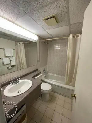 a bathroom with a sink and a toilet and a tub at 6032 Persepolis Inn in Niagara Falls