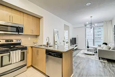 a kitchen with stainless steel appliances and a living room at Prime Location - Stunning 2-bdrm Condo in Toronto