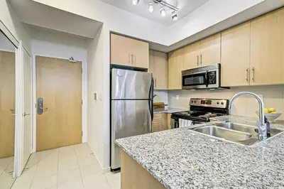 a kitchen with a stainless steel refrigerator and a sink at Prime Location - Stunning 2-bdrm Condo in Toronto