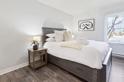 a bedroom with a large bed with white sheets and a table at Mountain Walk Chalet Across From Blue Mtn Village in Blue Mountains