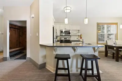 a kitchen with a counter and two bar stools at Blue Mtn Getaway in Historic Snowbridge Chalet in Collingwood