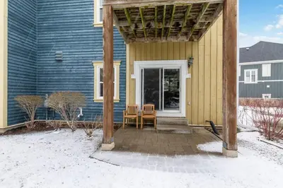 a porch of a blue house with a table and chairs at Blue Mtn Getaway in Historic Snowbridge Chalet in Collingwood