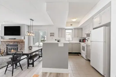 a white kitchen with a table and a fireplace at Condo With Blue Mtn Village In Your Backyard in Blue Mountains