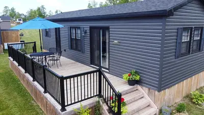a black house with a deck with a table and an umbrella at Bellmere Winds Resort in Keene