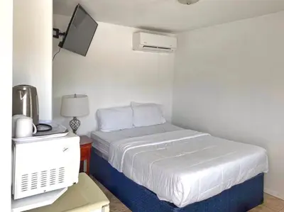 a small bedroom with a bed and a tv at Sunny Motel Port Elgin in Port Elgin