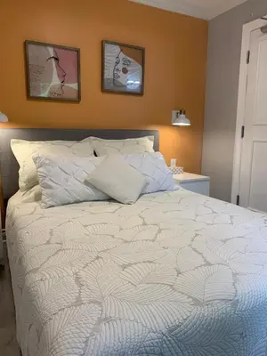 a bedroom with a white bed with two pictures on the wall at Ambiance by the Falls Cozy Suite in Niagara Falls