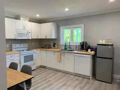 a kitchen with white appliances and a wooden table at Ambiance by the Falls Cozy Suite in Niagara Falls