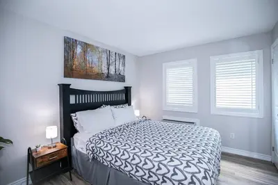 a bedroom with a large bed and two windows at Slopeside Sanctuary - Ski In/Ski Out in Blue Mountains