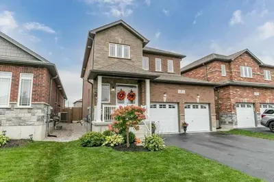 a brick house with two white garage doors at Cozy 3 bedroom home perfect for small gatherings in Barrie