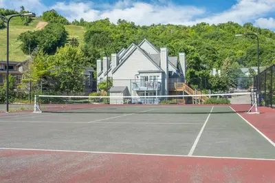 a tennis court with a house in the background at Blue Mountain Luxury Studio in Blue Mountains