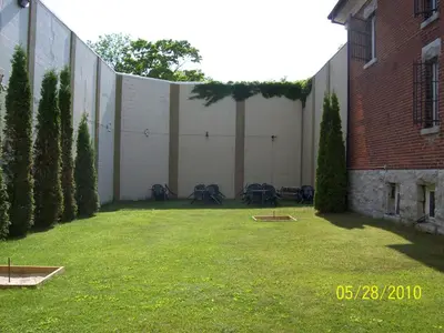 a large white wall with tables and chairs in a yard at The King George Inn in Cobourg