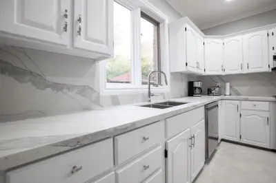 a white kitchen with white cabinets and a window at Niagara Luxury Suites in Niagara Falls