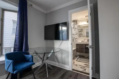 a room with a glass table and a blue chair and a television at Niagara Luxury Suites in Niagara Falls