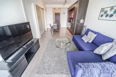a living room with a blue couch and a flat screen tv at RHD Luxury Condos-Downtown, CN Tower, Metro Toronto Convention Centre, Rogers Centre, Free Parking in Toronto