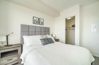 a white bedroom with a large bed and a mirror at RHD Luxury Condos-Downtown, CN Tower, Metro Toronto Convention Centre, Rogers Centre, Free Parking in Toronto
