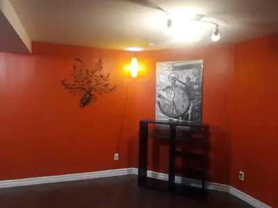 a room with orange walls and a clock on the wall at ZARA's UNIQUE APARTMENT in Mississauga