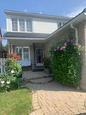 a house with a hedge with flowers on it at BIG Oasis Studio near Airport YYZ in Toronto