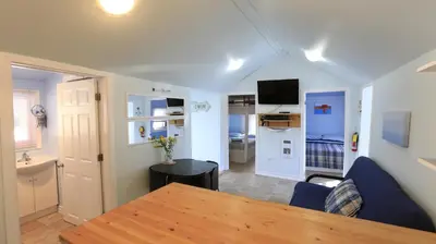 a living room with a table and a kitchen at Plovers Cove Cottage in Wasaga Beach