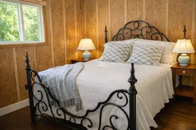 a bedroom with a black bed with two lamps on tables at Spacious 3 Plus 1 Bedroom 2 Bath Cottage Retreat with Fire Pit and Pool Table in Brighton