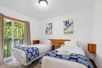 two beds in a room with a window at 10 Bedroom Executive Chalet w Hot Tub in Blue Mountains